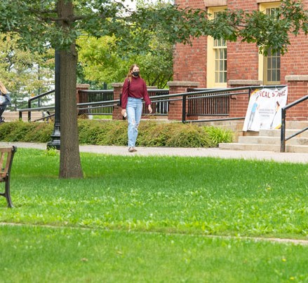 a student walks across campus in front of SDU main building
