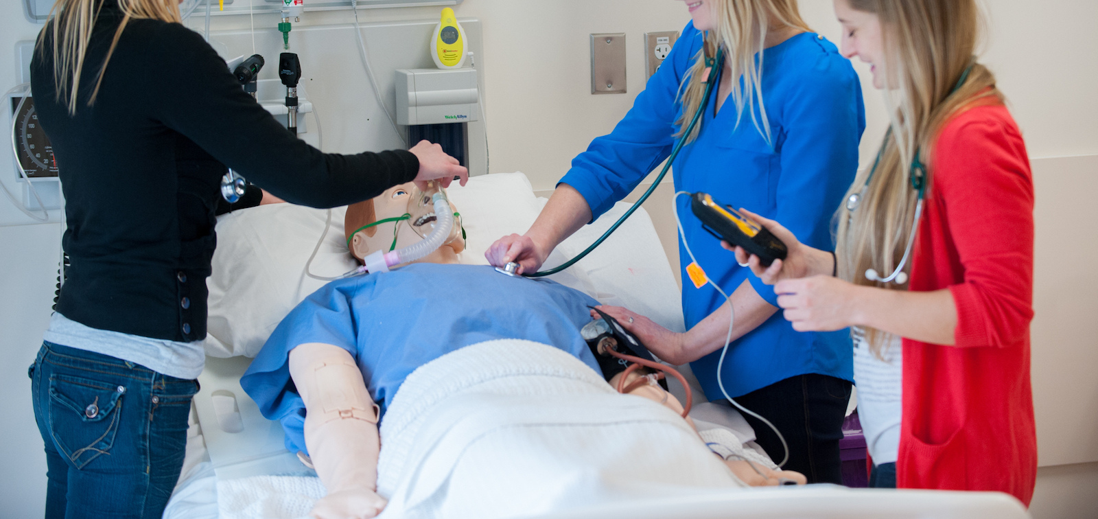 three nursing students with clinical mannequin