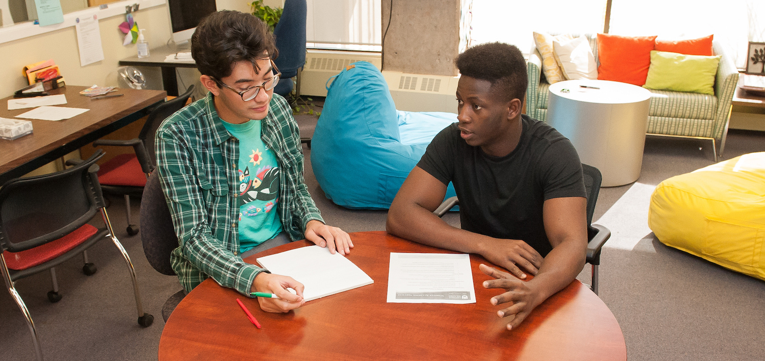 students sit at a desk writing