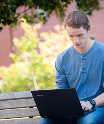 A student works on a computer on a bench