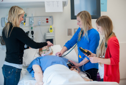 three nursing students with clinical mannequin