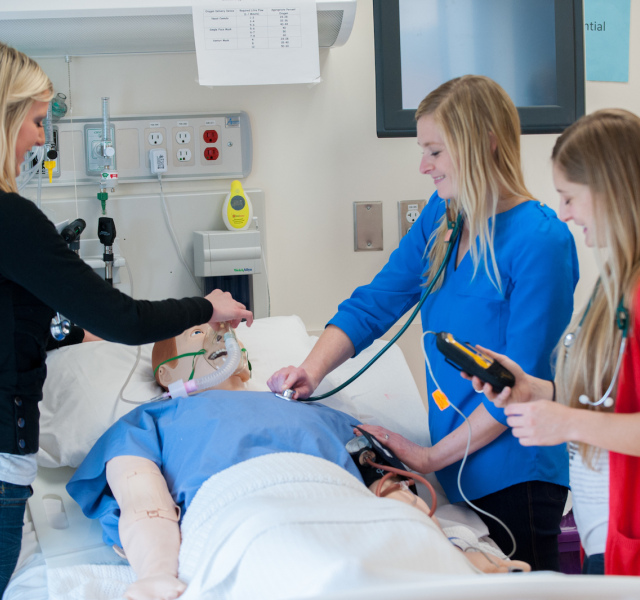 three nursing students with clinical mannequin