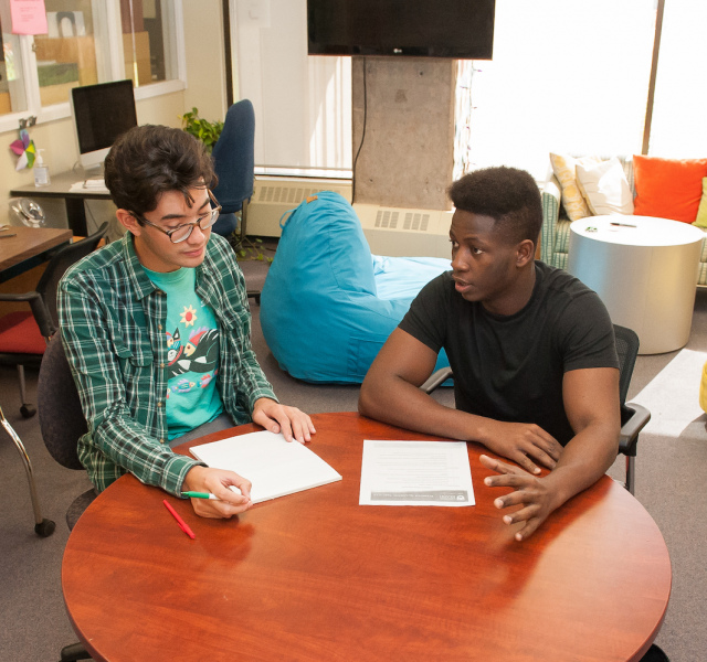 students sit at a desk writing